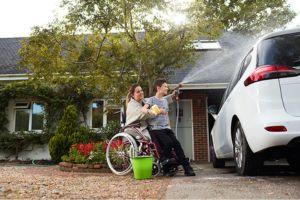 woman in wheelchair washing car